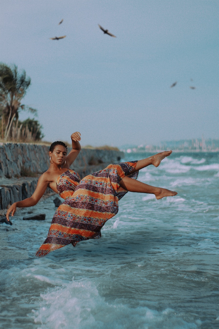 woman with a pixie cut falling into sea with flowing dress on looking relaxed