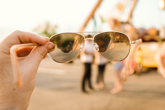 Sunglasses being held in front of people standing in a group